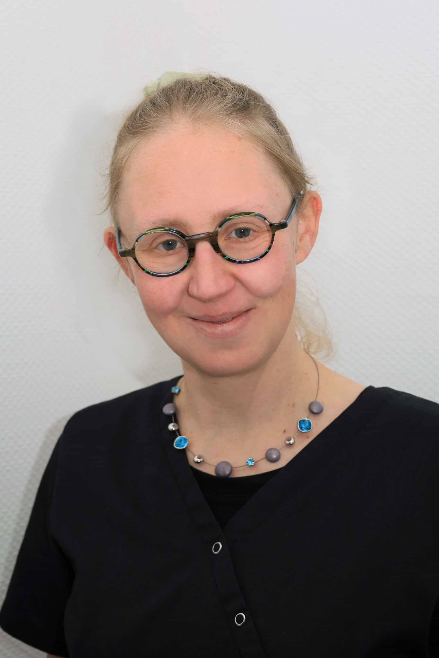 Freundliche Arzthelferin in Praxis mit Brille.