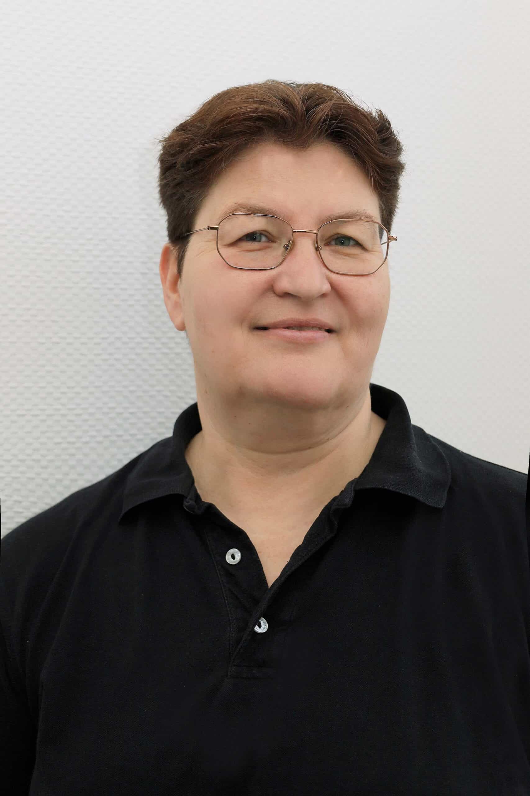 Ärztin in schwarzem Polo vor weißem Hintergrund.