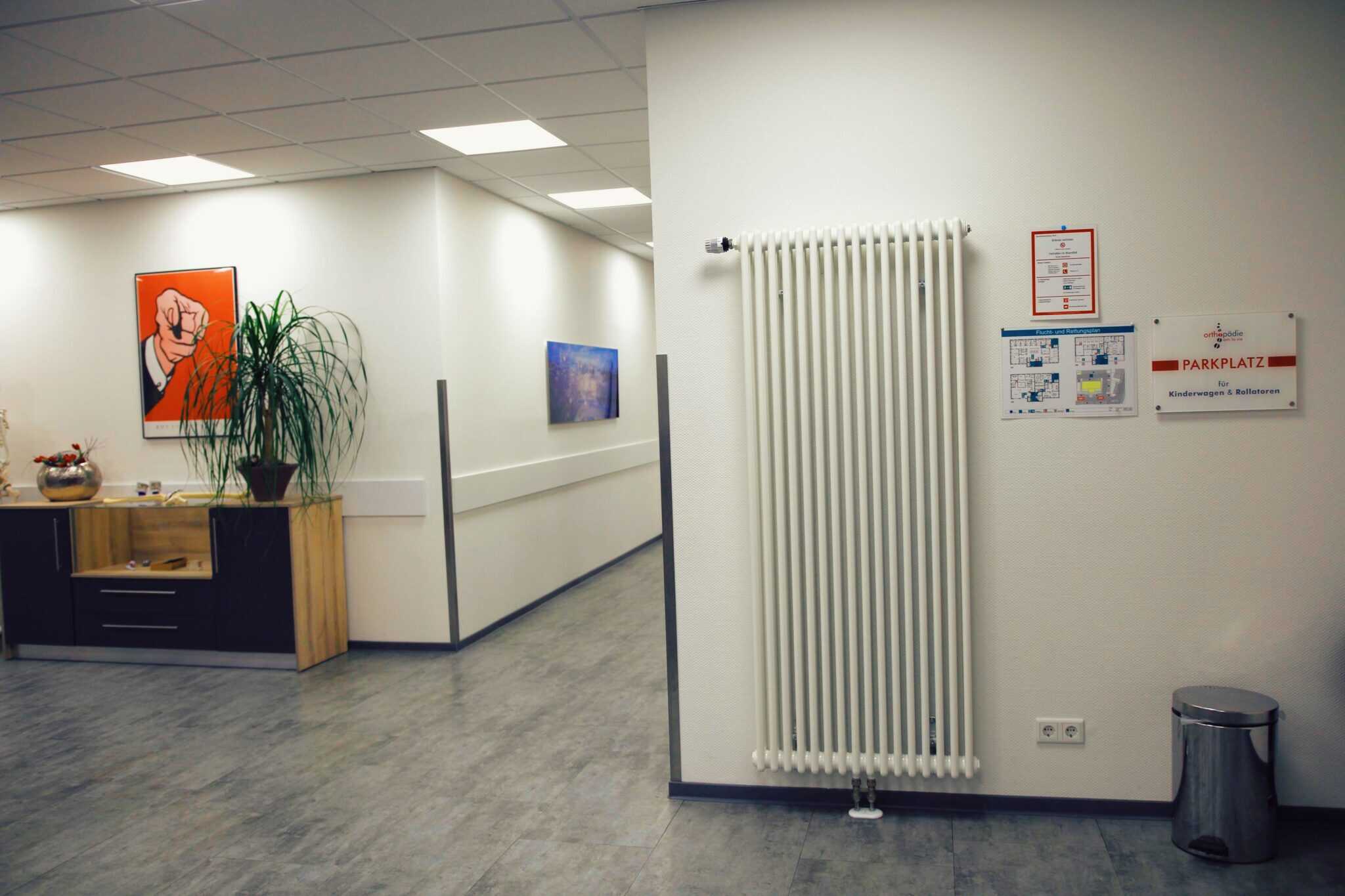 Modernes Praxisinterieur mit Kunstwerken und Heizkörper.