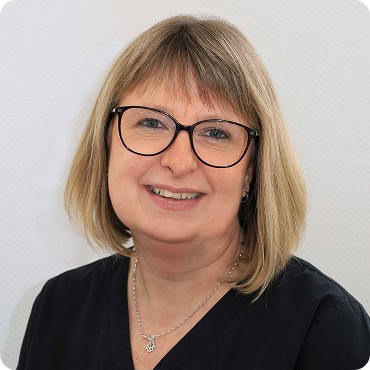 Arzthelferin mit Brille lächelnd, freundliches Team.