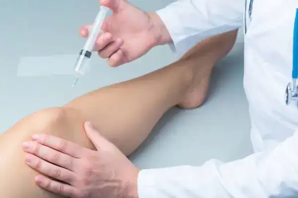 Arzt verabreicht Injektion in das Kniegelenk.