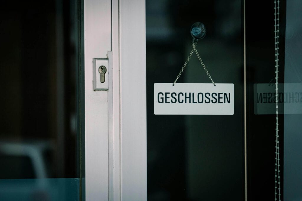 Ein weißes Schild mit der Aufschrift "geschlossen" hängt an einer Glastür
